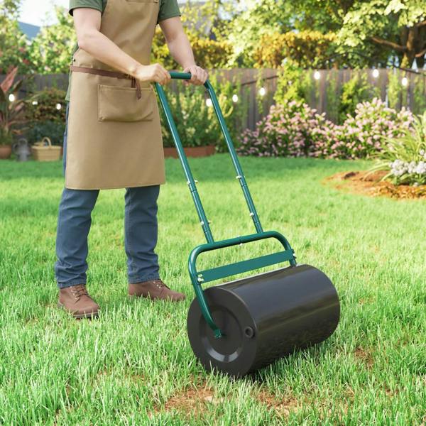 Dark green push lawn roller with black cylinder drum on green grass