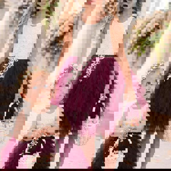 Two young girls in matching dresses with floral headbands and baskets, standing indoors.