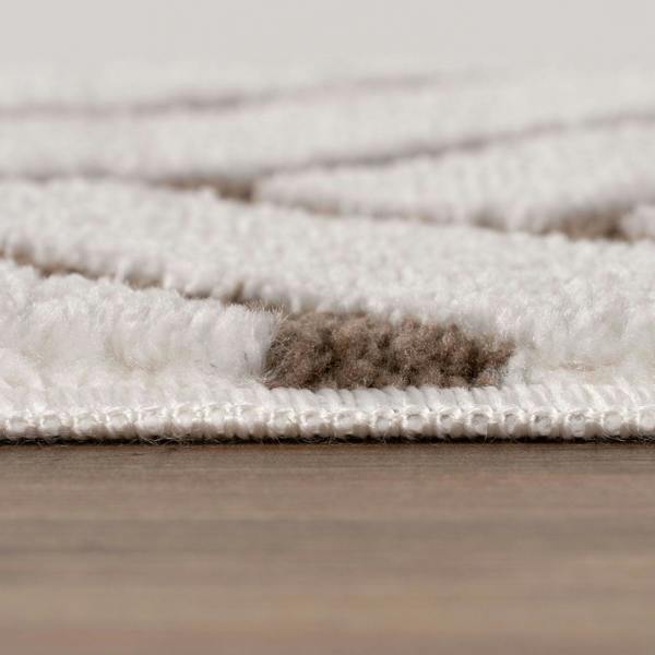 Close-up of a textured rug with a neutral color palette on a wooden floor.
