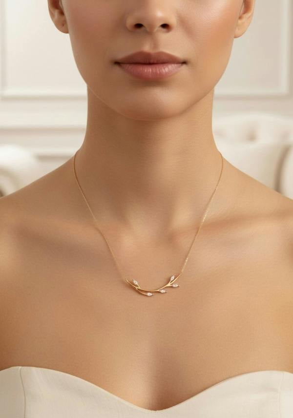 Close-up of a person wearing a delicate gold necklace against a neutral background