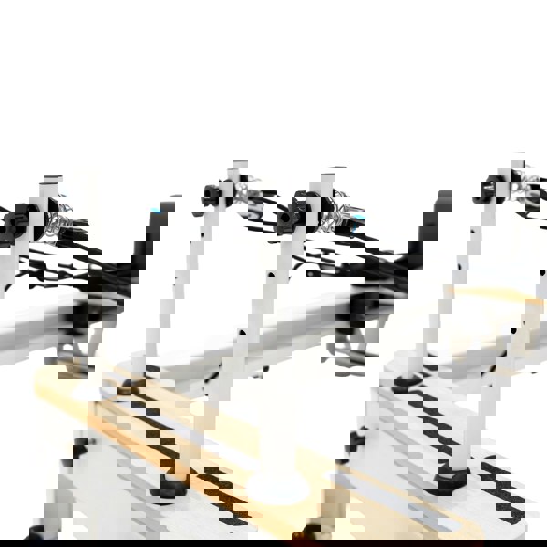 Aluminium Pilates reformer machine with adjustable vertical posts, black rubber feet, and smooth wooden surface for stability and comfort