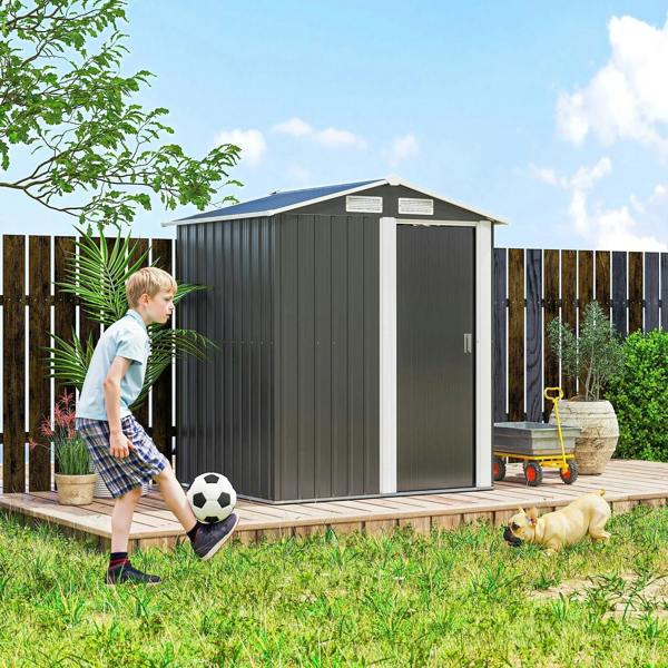 Grey metal storage shed with sliding door closed on wooden platform in a garden