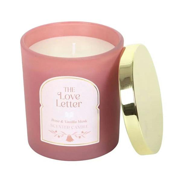 Pink candle jar with lid off; flame visible and front label