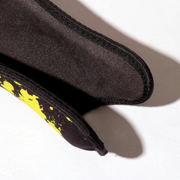 Close-up of black Optimum Fusion hockey shin guard padded reverse with yellow splatter edge, on white - Optimum