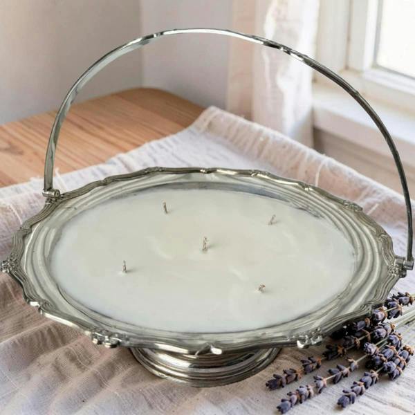 Decorative candle in a silver holder on a wooden surface with lavender flowers.