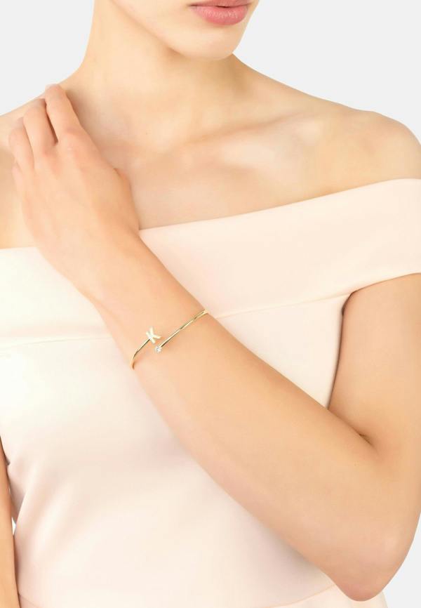 Gold bracelet on a person's wrist with a plain background