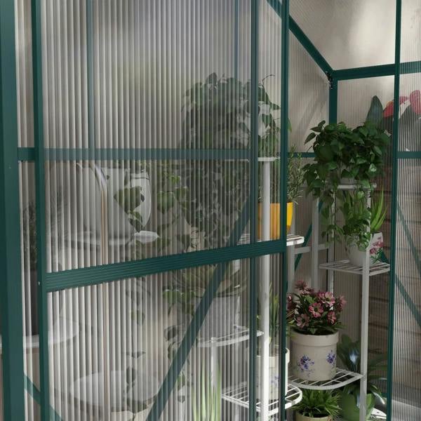 Green polycarbonate greenhouse interior with transparent walls and potted plants