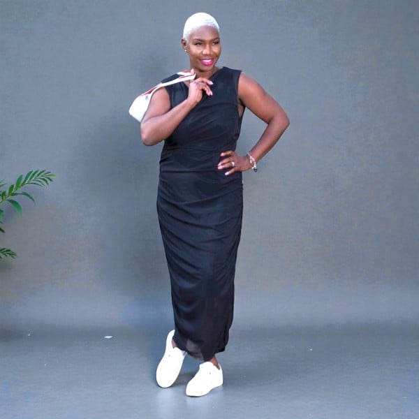 Women's Plus Size Summer Black Ruched Bodycon Midi dress styled with a white handbag and white sneakers for a chic, modern ensemble.