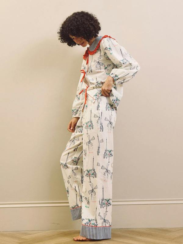 Woman wearing a Paris themed printed pyjama set with a large collar with red frill against a beige background