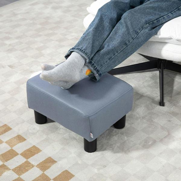 Grey rectangular footstool supporting bare feet on the padded top