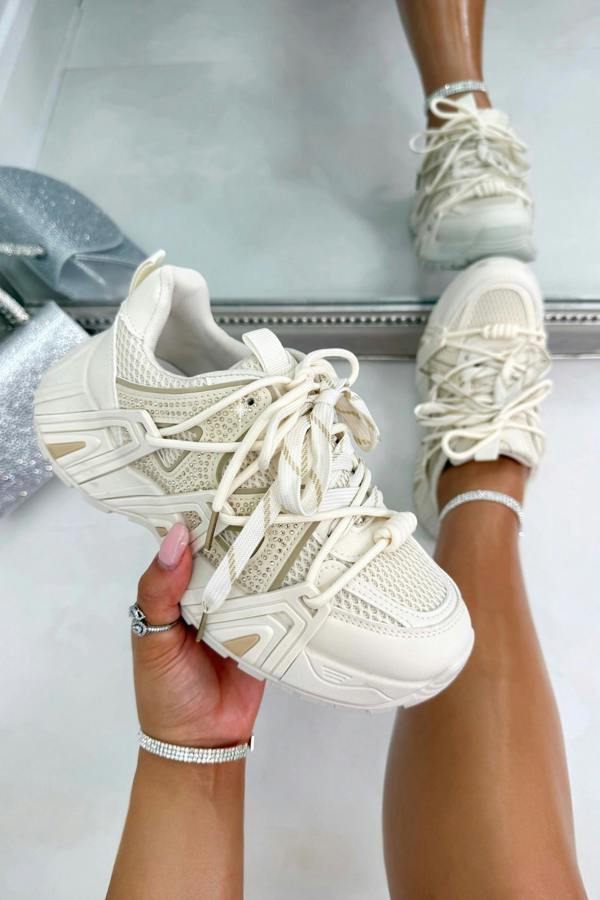 Beige sneakers being held with a blurred background