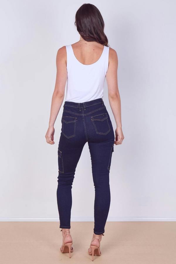 Woman wearing dark blue jeans and a white tank top on a plain background