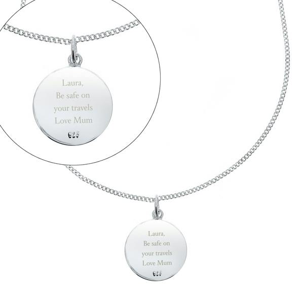 The sterling silver reverse side of a circular St. Christopher pendant by Abode Home & Gifts, displayed on a matching silver chain over a clean white background. An inset circle zooms in on the custom engraving reading "Laura, Be safe on your travels Love Mum".