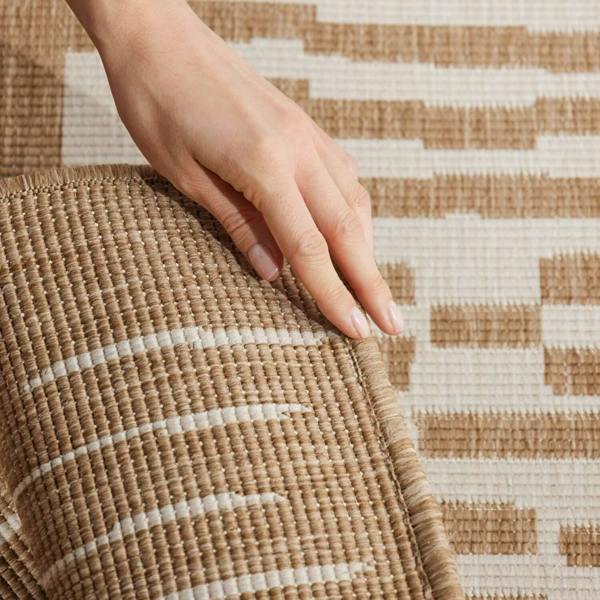 Hand touching a woven mat with a geometric pattern