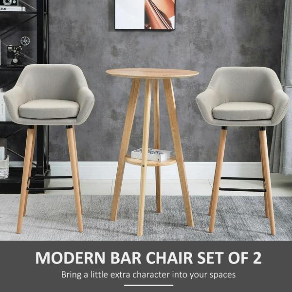 Set of 2 beige upholstered bar chairs with curved arms, light wood legs, and black footrests
