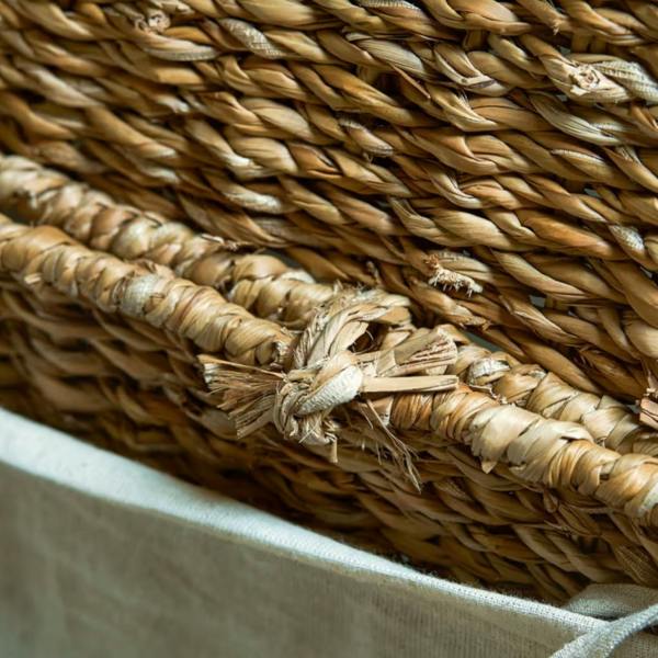 Macro close-up of the hand-tied woven seagrass hinge attachment on the laundry hamper lid above the cotton liner.