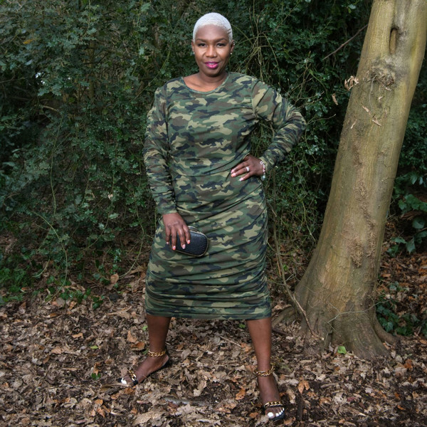 Women's Plus Size Olive Green Camouflage Bodycon Midi Dress styled with gold chain heels and a black and gold clutch for a sophisticated touch.