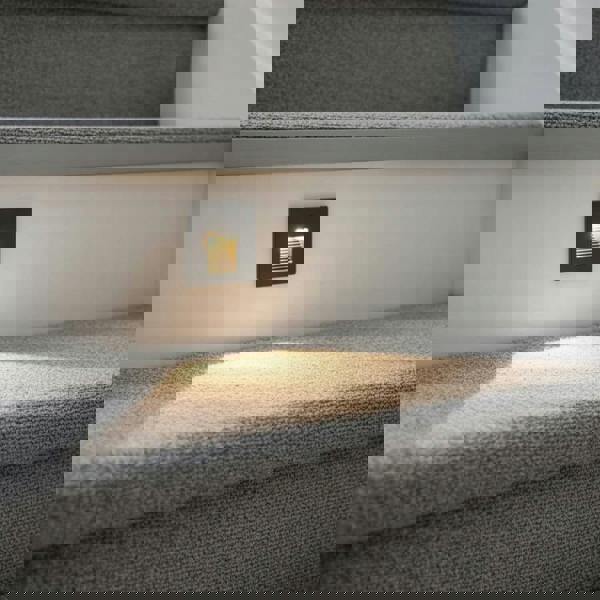 black motion sensor light for stairs installed into a home stair riser