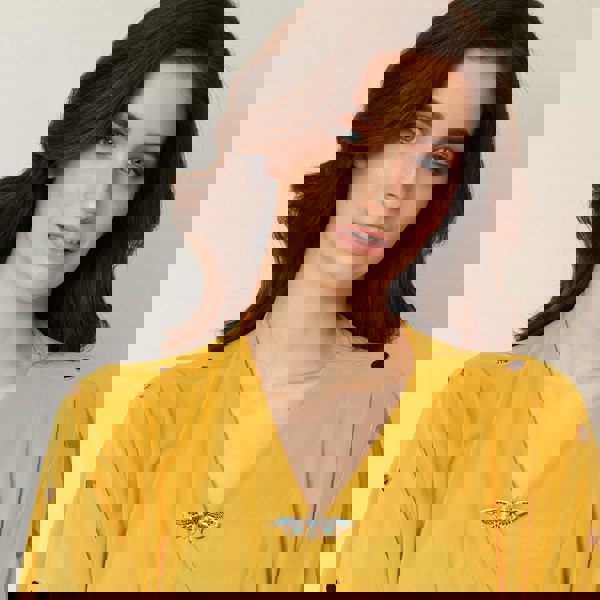 moth brooch in blue enamel worn on gold dress for wedding guest