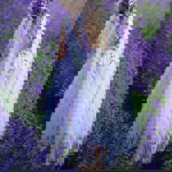 Girl in a lavender dress standing among lavender flowers