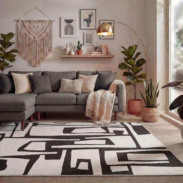Modern living room with a gray sectional sofa, geometric rug, and decorative elements.