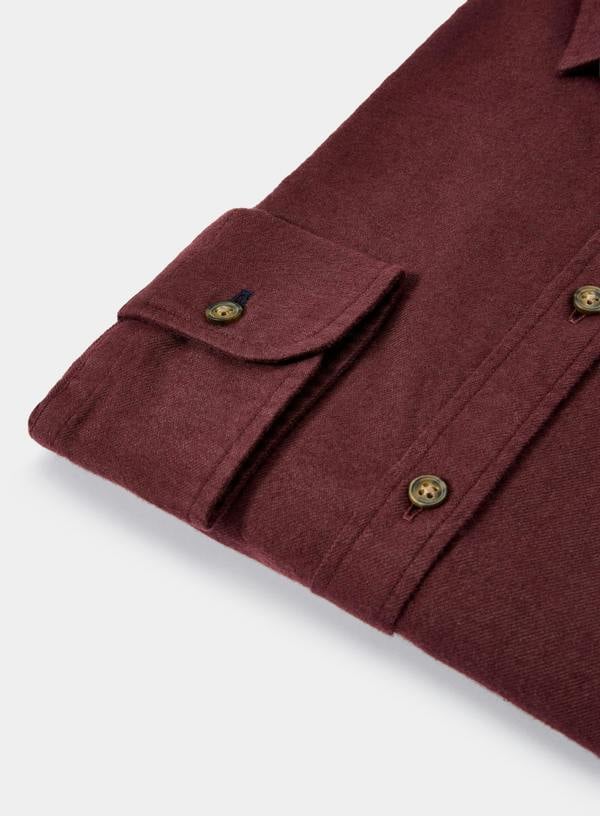 Close-up of a burgundy shirt with button details on a light gray background