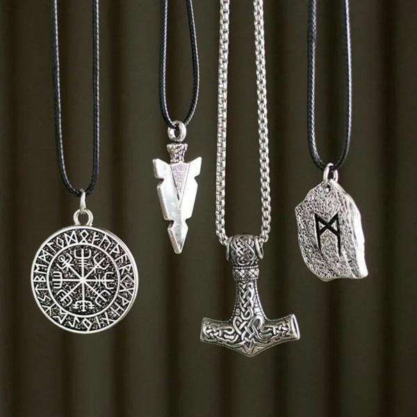 Assorted silver rune pendants on black cords and chains, featuring compass and shield charms.