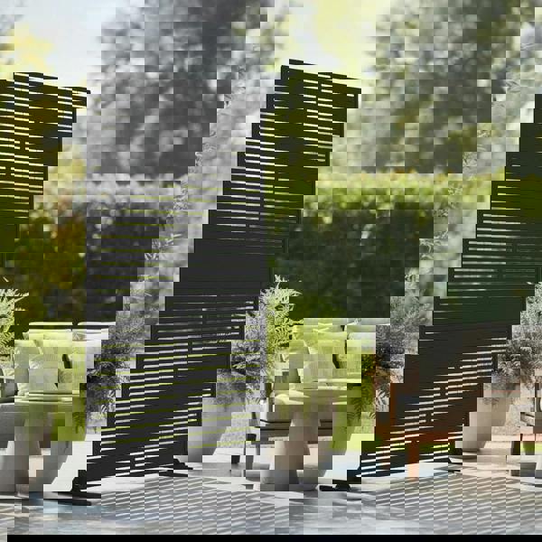 Black slatted privacy screen in an outdoor setting with a sofa and plants.