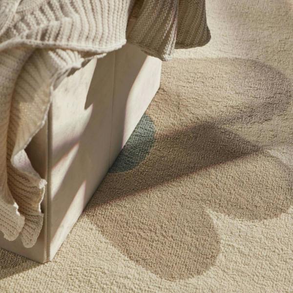 Close-up of a textured beige fabric with a white box and a beige sweater on a matching background.