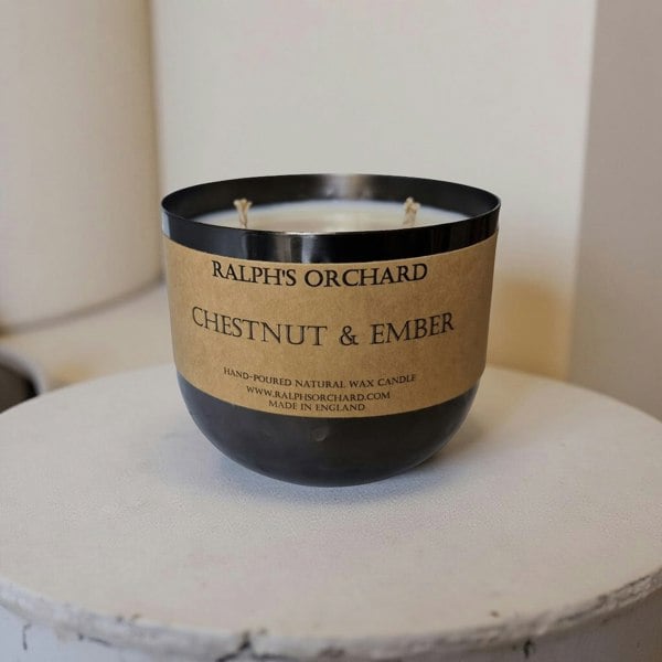 Candle with 'Ralph's Orchard' label on a white surface