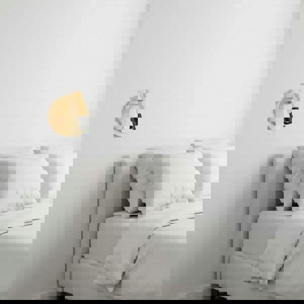 black adjustable wooden reading lamp fitted on the wall next to the bed in a bedroom