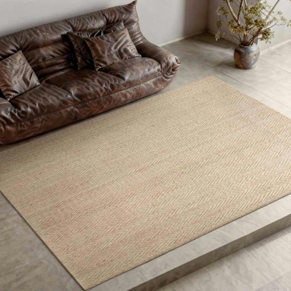 Beige rug on a wooden floor with a brown leather sofa and decorative plant in the background.