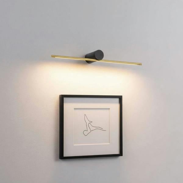 gold picture light fixture mounted on the wall over some modern artwork 