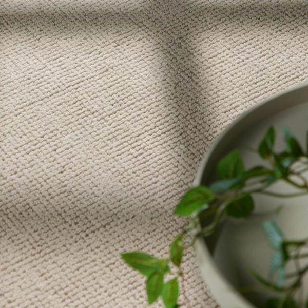 Close-up of textured beige fabric with a plant in the corner
