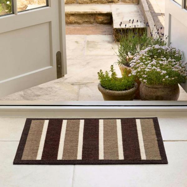 Striped doormat in front of a glass door with plants on a patio