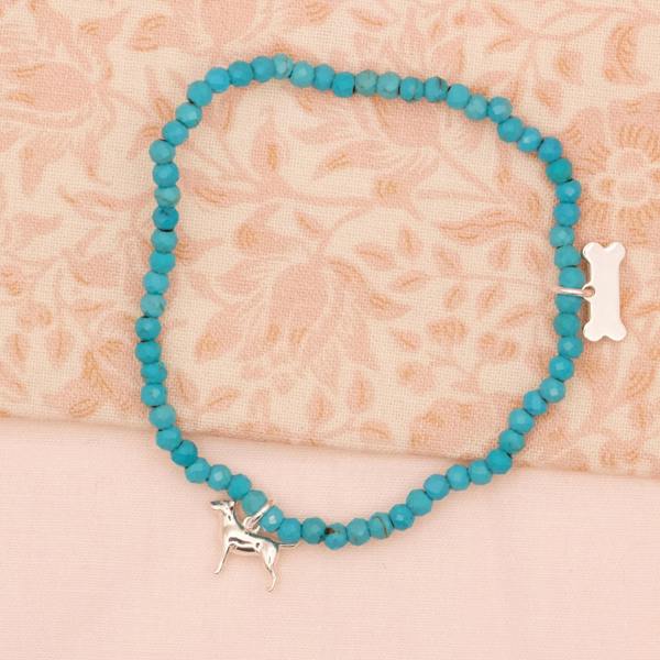 Turquoise beaded bracelet with a silver bull terrier dog charm on a beige floral background