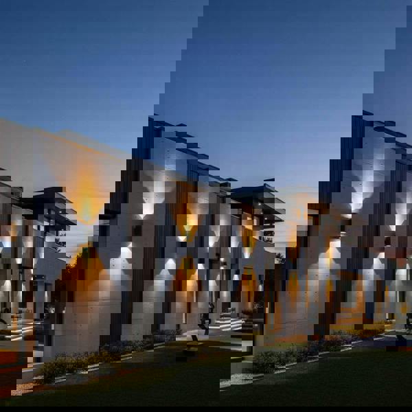 black large outdoor wall light mounted in a line along the exterior wall of a large modern home