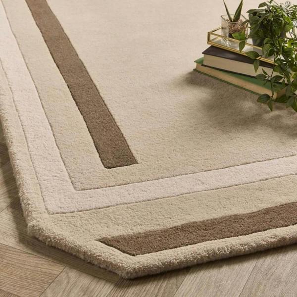 Beige and brown striped rug on a wooden floor with books and plants.
