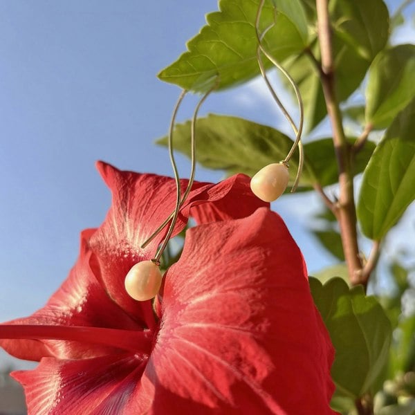 Pearl threader earrings in luxury gold vermeil against a vibrant red flower.