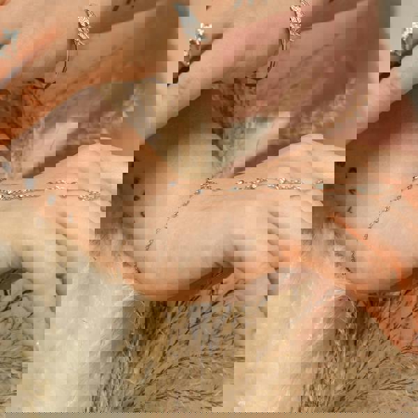 Close-up of a hand wearing a delicate bracelet with a soft background. Adjustable sterling silver hand chain by BLOOMTINE with 6 lab-grown diamonds. Known as a finger chain or hand harness, this tarnish-resistant rhodium-plated piece features a diamond-cut chain for maximum sparkle, fitting wrist sizes 5.75 to 7.5 inches