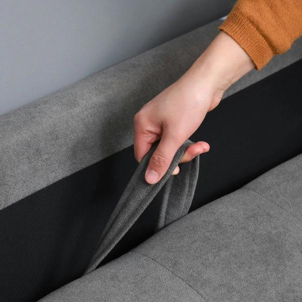 Hand pulling a tab on the grey sofa, opening the hidden storage compartment
