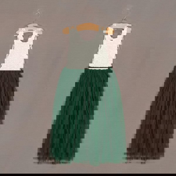 Green dress with white lace top on a hanger against a brown background