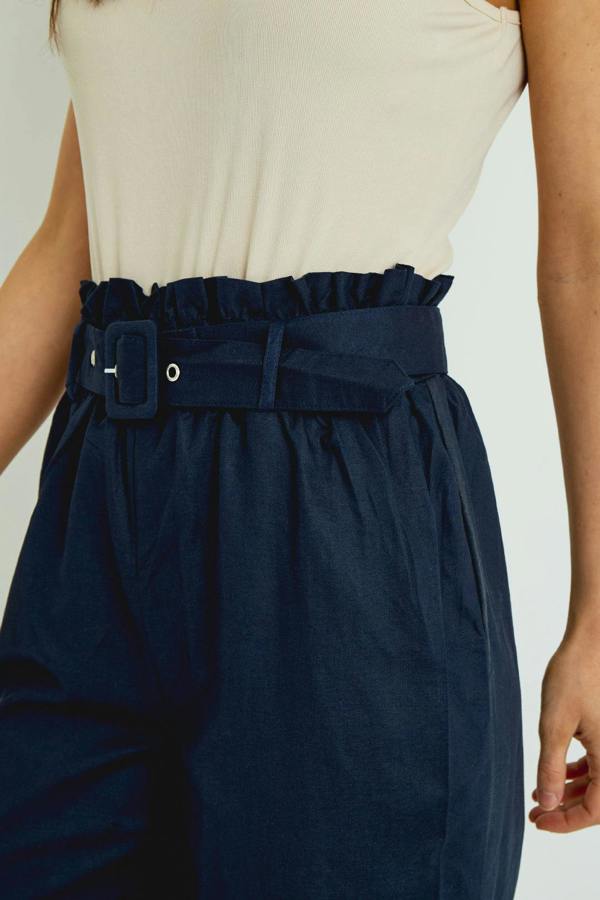 Navy paperbag pants with a belt on a plain background