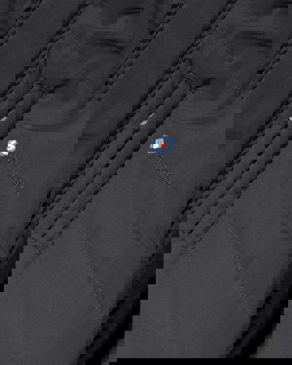 Lambretta Mens Padded Hooded Classic Badge Parka, close-up of the black jacket's front pocket with embroidered Lambretta logo and patch detail.