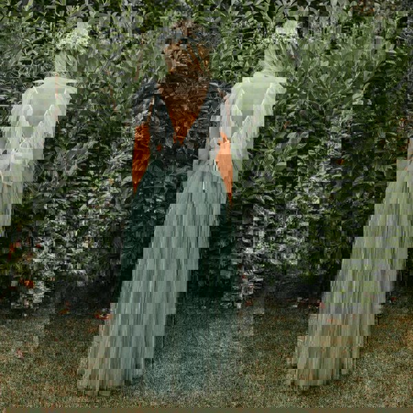 Girl in a garden wearing a Bohemian Serendipity Dress in sage green