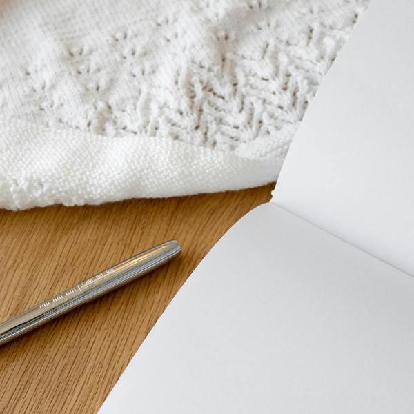 Close-up of open blank luxury pages of the Personalised Christening Guest Book with a silver pen on a wooden surface.
