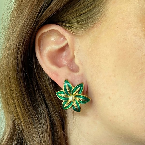 Green clip-on earrings, floral design, glossy enamel petals, gold-tone detailing, central pearl accent, bold vintage-inspired accessory
