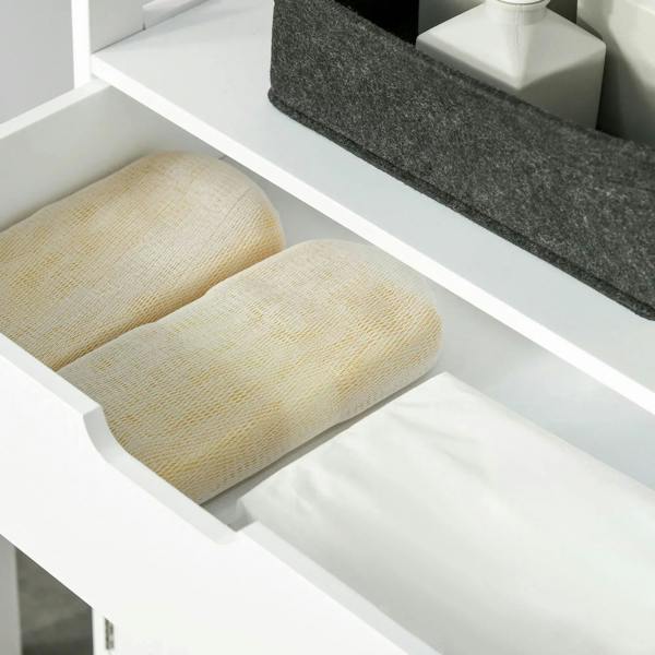 White cabinet drawer interior with folded light-yellow and white towels on a shelf