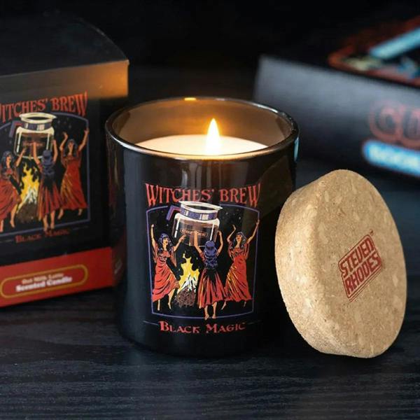 Black jar candle with cork lid, Witches' Brew artwork, flame lit