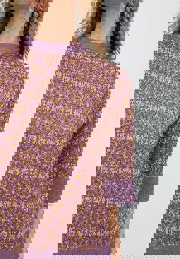 Purple patterned sweater worn by a person on a light gray background